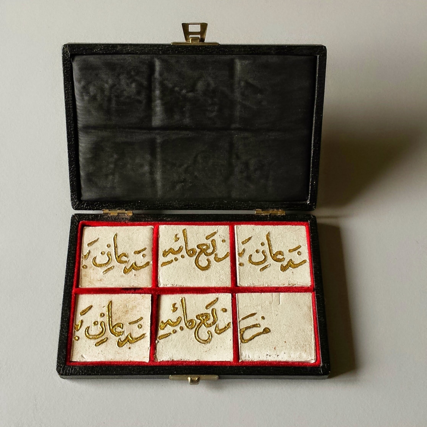 Calligrafia antica, Particolari di calligrafia araba antica dorata, incisa su quadrati di creta bianca poi inseriti in una scatola foderata in pelle.